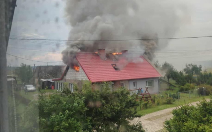 Dom w płomieniach, wydobywający się dym z dachu.