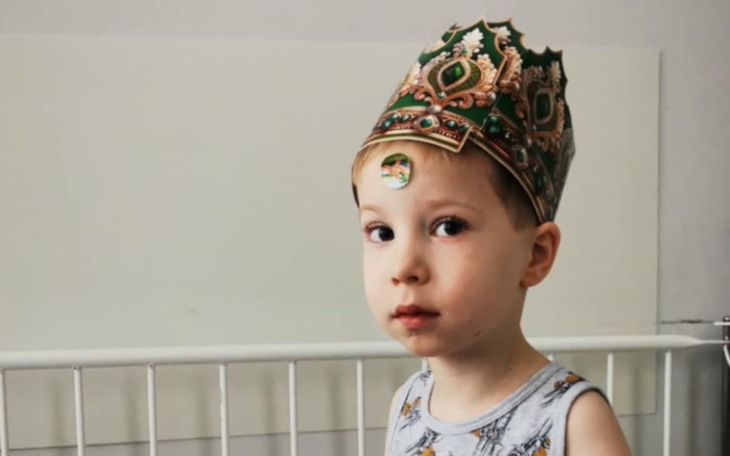 Chłopiec w koronie, uśmiechający się do kamery.