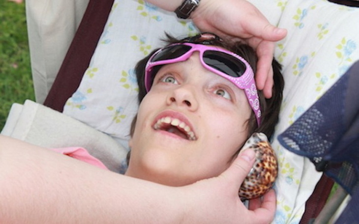 Dziewczyna leżąca na leżaku, z muszlą w ręku.