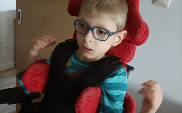 Chłopiec w wózku, z okularami, wyraża emocje.