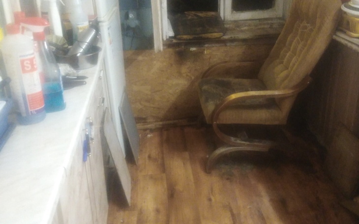 Widok na zniszczoną podłogę w kuchni z krzesłem.