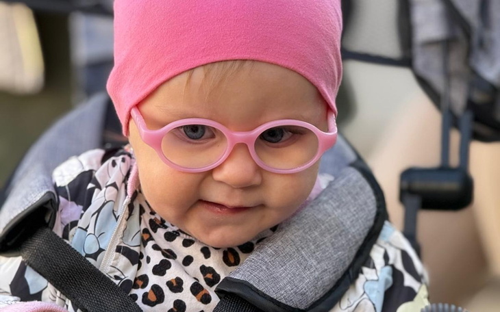 Mała dziewczynka w różowych okularach, uroczy uśmiech.