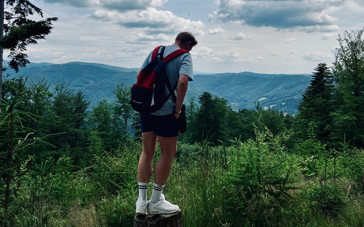 Mężczyzna na szczycie wzgórza, podziwiający widoki górskie.