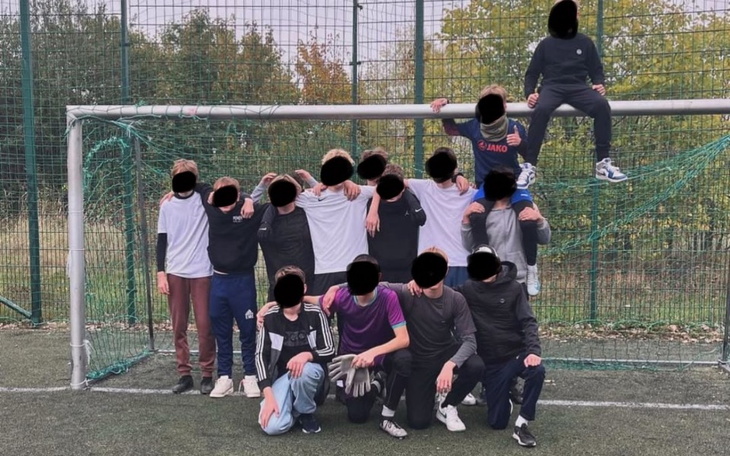 Grupa dzieci grających w piłkę nożną na boisku.