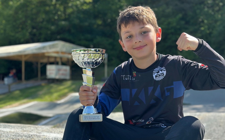 Chłopiec z pucharem, dumnie pokazujący swoje osiągnięcie.