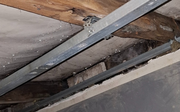 Widok na drewniane belki i metalowe elementy konstrukcyjne.