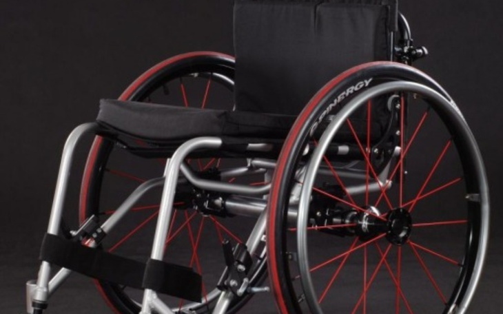 Wózek inwalidzki z czerwonymi akcentami na czarnym tle.