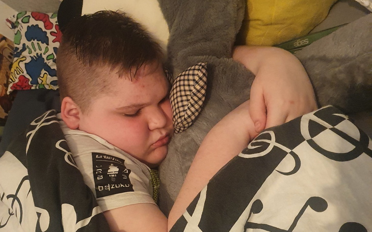 Chłopiec śpiący z pluszowym misiem w ramionach.