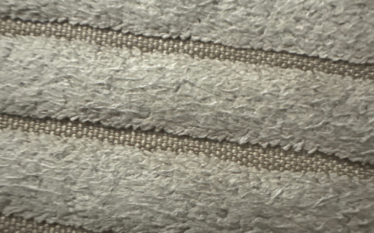 Zbliżenie na teksturę materiału, w odcieniach szarości.