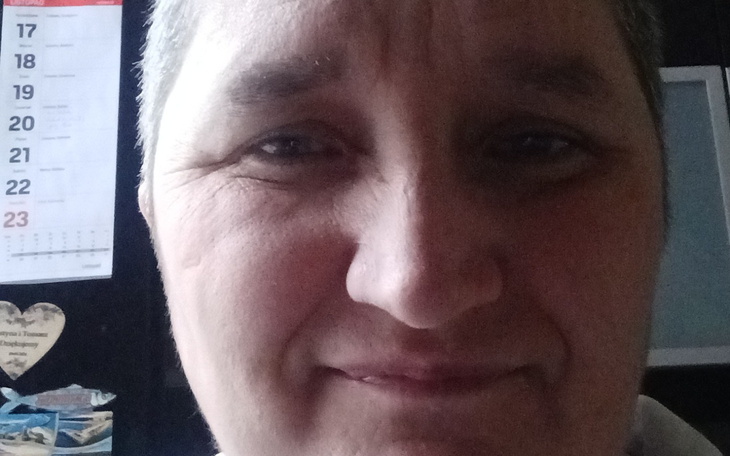 Portret uśmiechniętej kobiety w domowym otoczeniu.