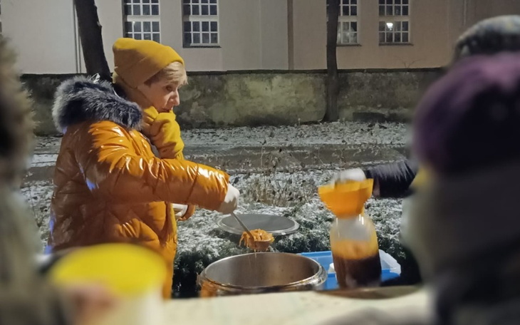 Osoba serwująca jedzenie w zimowej scenerii.