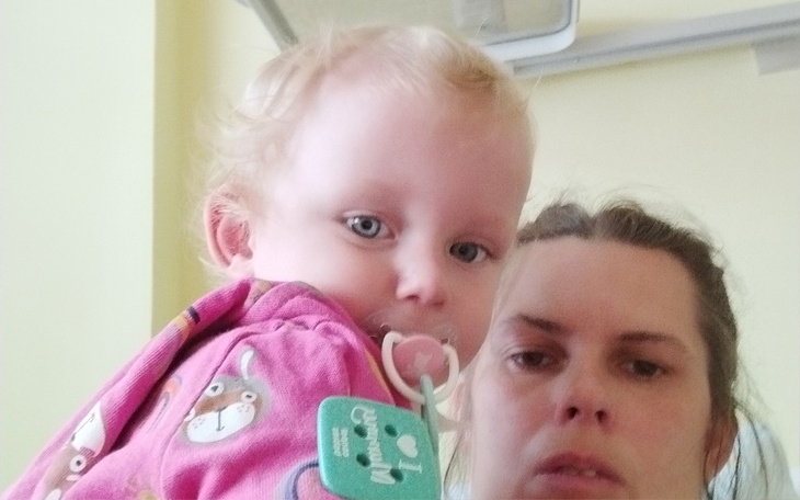 Dziecko trzymane przez dorosłego, oboje w szpitalu.