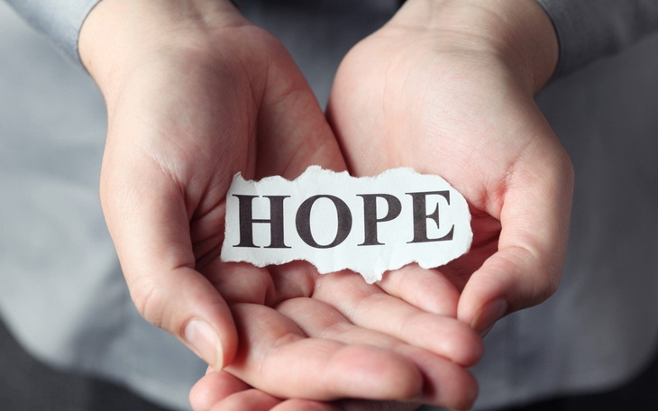 Ręce trzymające kartkę z napisem 'NADZIEJA'.