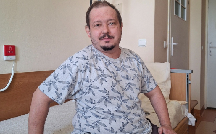 Pies leżący na podłodze, widać balkon i zabudowę w tle.