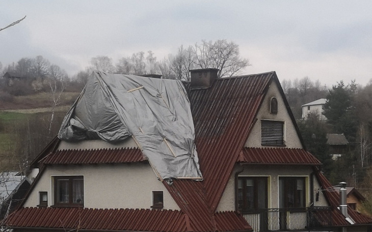 Dom z uszkodzonym dachem przykrytym folią.