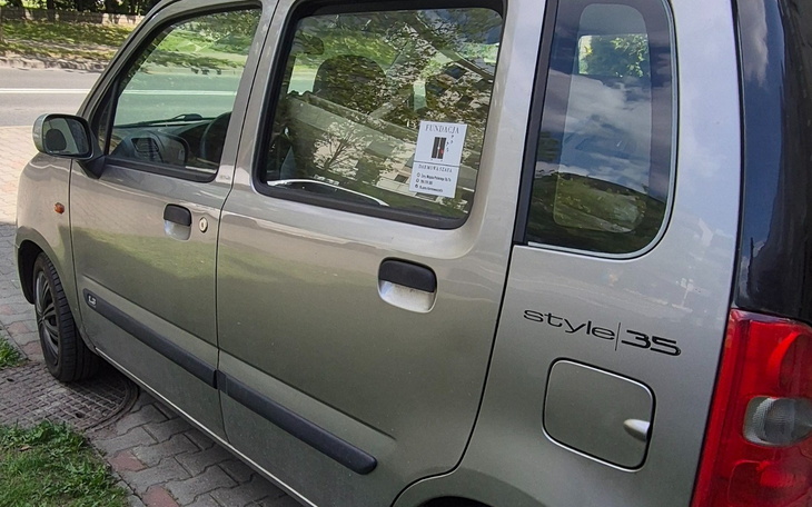 Samochód zaparkowany na chodniku z widoczną kartką informacyjną.