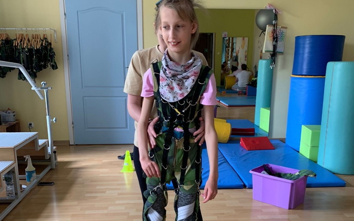 Dziewczynka w specjalnym kombinezonie rehabilitacyjnym.
