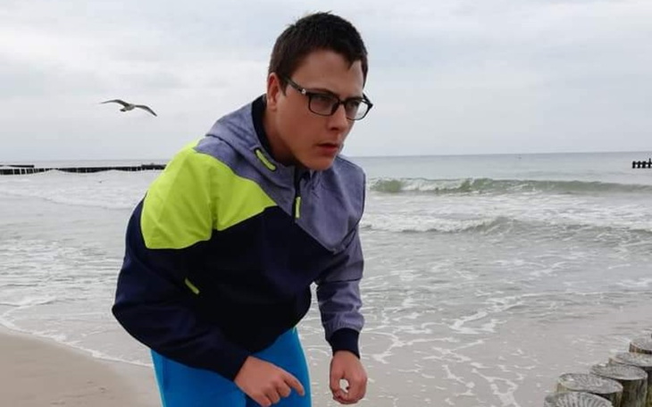 Młody mężczyzna na plaży, zaskoczony przez falę.