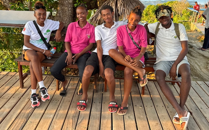 Grupa pięciu osób na tarasie, uśmiechających się do kamery.