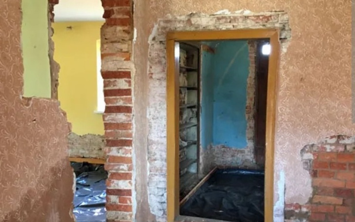 Zniszczony pokój z odsłoniętymi ścianami i drzwiami.