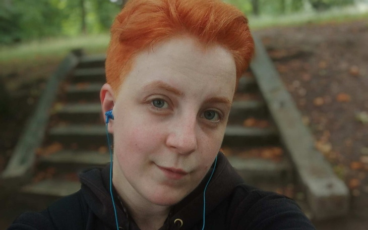 Młoda osoba z pomarańczowymi włosami, słuchająca muzyki.