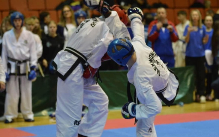 Zawodnicy taekwondo w trakcie walki na zawodach sportowych.