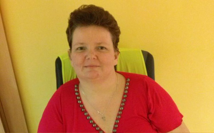 Uśmiechnięta kobieta w czerwonej bluzce na tle żółtej ściany.