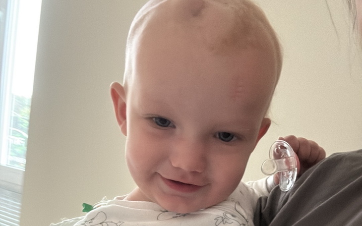 Małe dziecko z uśmiechem, trzymające smoczek.