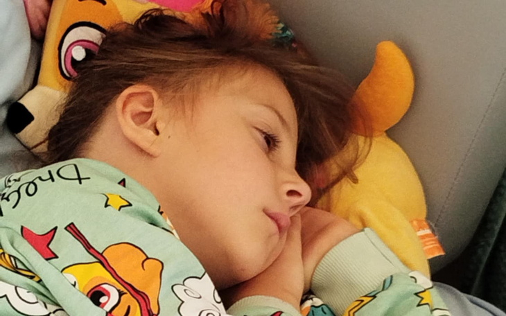 Dziecko śpiące na poduszce z pluszowym zwierzątkiem.