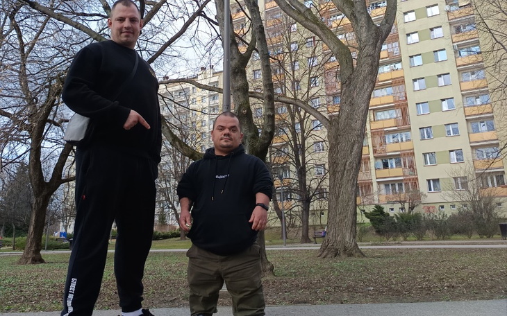 Dwaj mężczyźni pozują w parku, jeden z nich jest znacznie niższy.