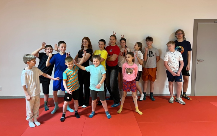 Grupa dzieci w sali, pozują do zdjęcia z uśmiechami.