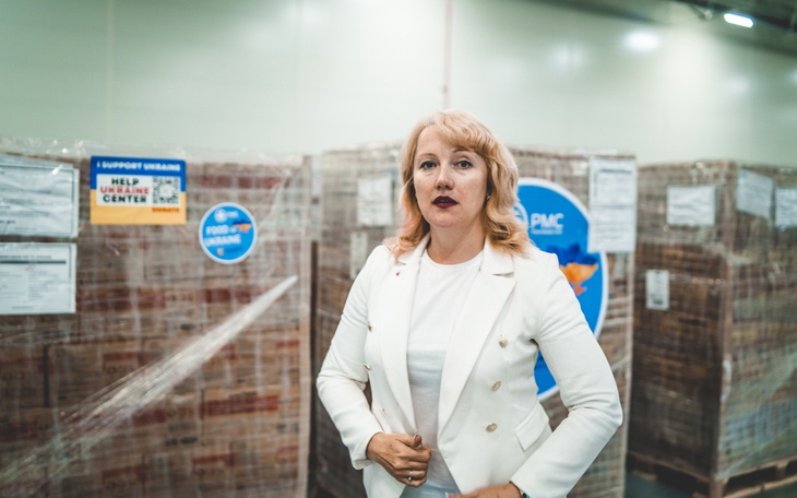 Kobieta w białym żakiecie w magazynie z paczkami.