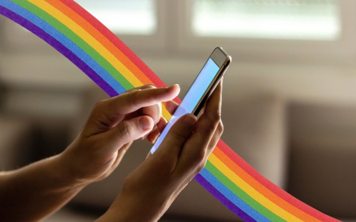Osoba korzystająca z telefonu, z tęczowym tłem.