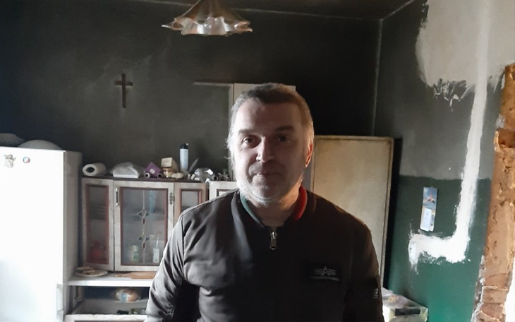 Mężczyzna w zniszczonym wnętrzu domu.