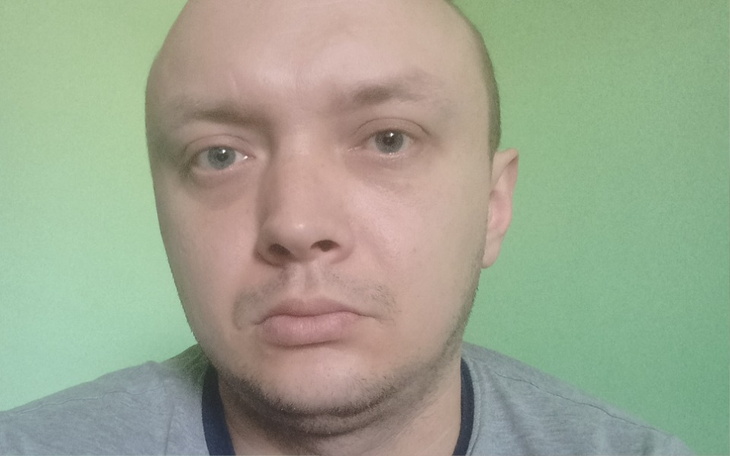 Mężczyzna z krótkimi włosami na zielonym tle.