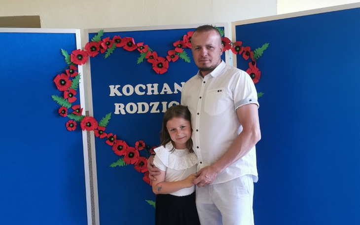 Mężczyzna z dzieckiem na tle dekoracji z czerwonymi makami.