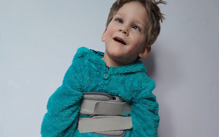 Chłopiec w niebieskim ubraniu, uśmiechający się z radością.