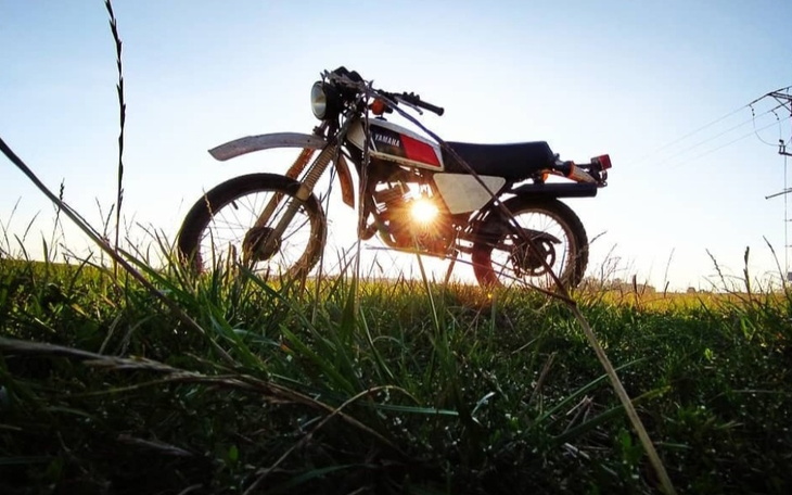 Motocykl Yamaha na tle zachodzącego słońca w polu.