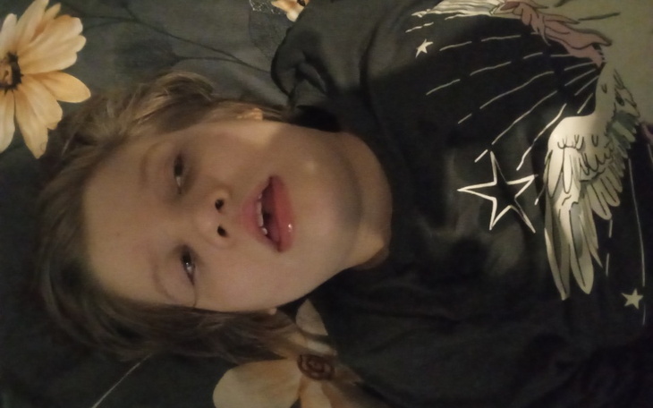 Chłopiec leżący na łóżku, z zamyślonym wyrazem twarzy.