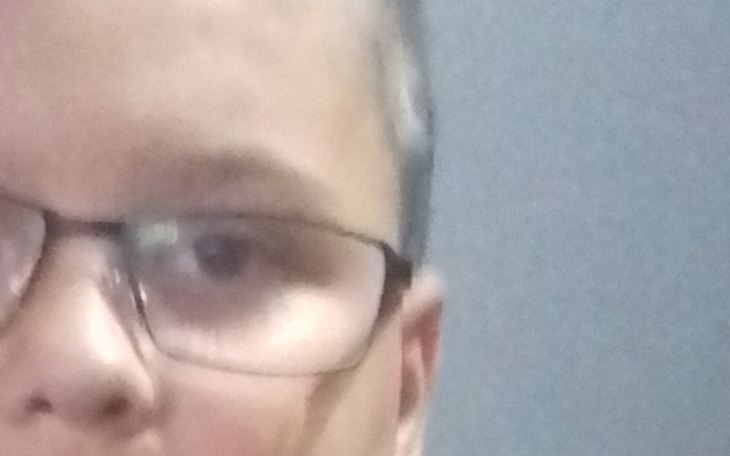 Chłopiec w okularach, z nieostrym tłem.