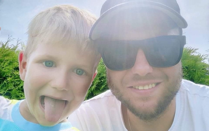 Mężczyzna z dzieckiem, obaj uśmiechnięci w słoneczny dzień.