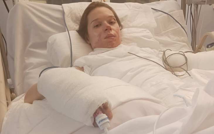 Kobieta w szpitalnym łóżku z opatrunkiem na ręce.