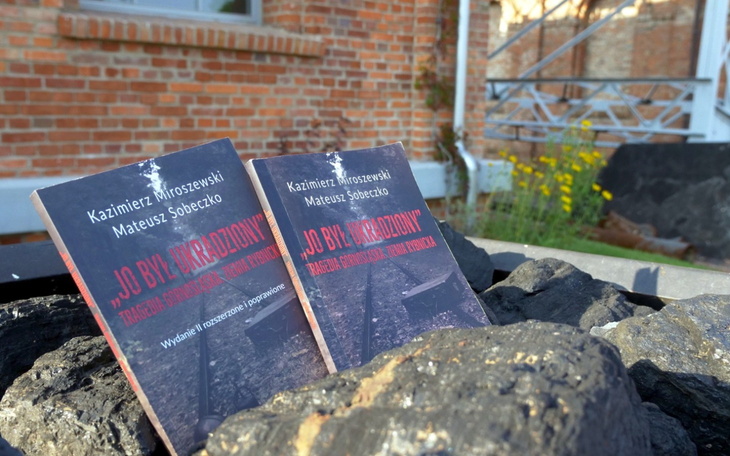 Książki leżące na kamieniach, w tle budynek.