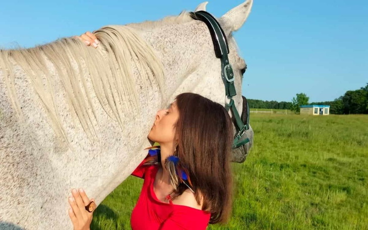 Kobieta przytulająca konia na zielonej łące, chwila bliskości.