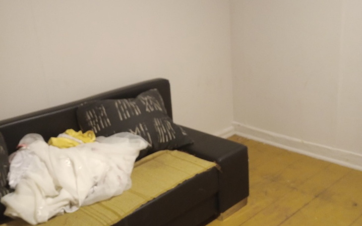 Pusty pokój z kanapą i nieuporządkowanymi rzeczami.