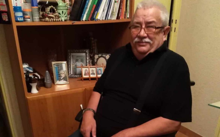 Starszy mężczyzna siedzący w fotelu, otoczony zdjęciami.