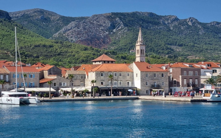 Widok na malowniczą miejscowość nadmorską z górami w tle.