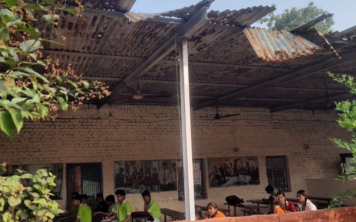 Zniszczony dach w klasie, uczniowie uczą się w trudnych warunkach.