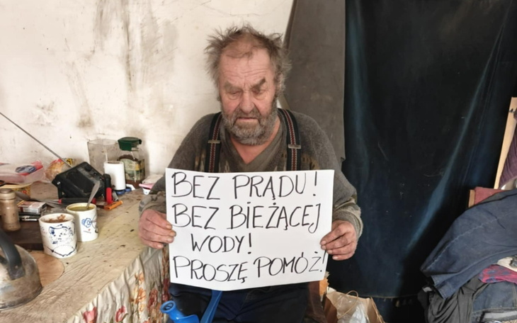 Mężczyzna z tabliczką, proszący o pomoc w trudnej sytuacji.