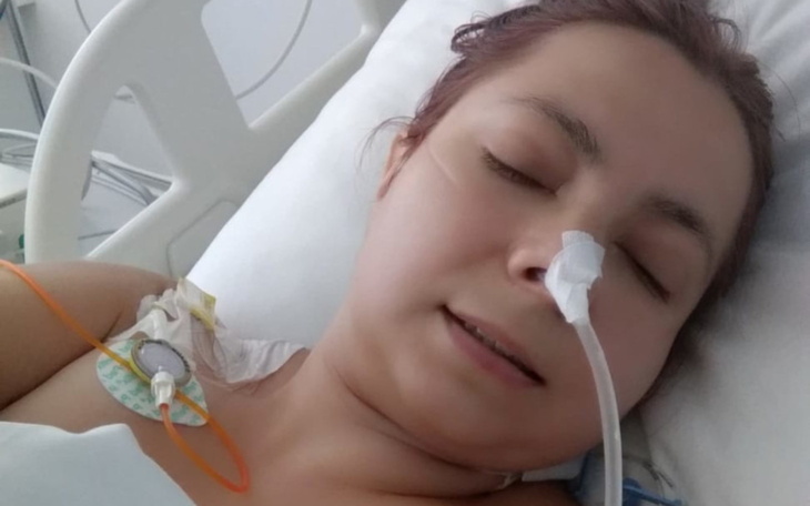 Kobieta w szpitalu, z rurkami medycznymi, leży na łóżku szpitalnym.